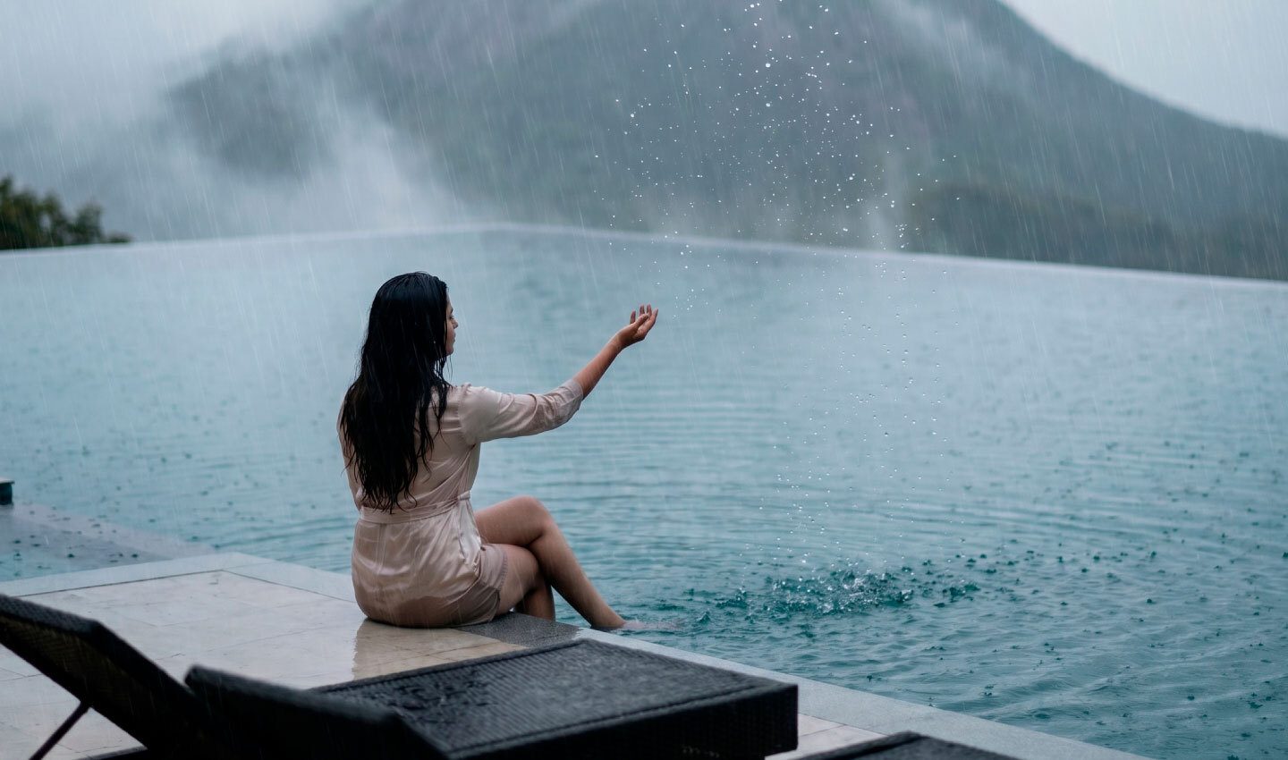 Real Lords83 guest enjoying peaceful moment at resort swimming pool overlooking misty Wayanad monsoon mountains - luxury pool suite experience